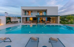A modern two-story house with a swimming pool, outdoor seating, and a view of the surrounding landscape. - Amazing home in Primosten (Primosten)