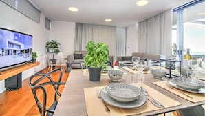 Una sala moderna con comedor, televisor y un ventanal con vistas.