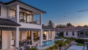 Ein modernes, zweistöckiges Haus mit Swimmingpool, Außenbereich zum Sitzen und einer überdachten Terrasse.