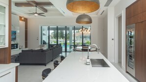 Eine moderne Küche mit Essbereich, großen Fenstern und Blick auf einen Pool.