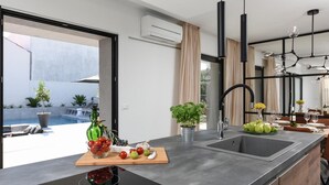 Una cocina moderna con una isla grande, un lavaplatos empotrado y vistas a una piscina exterior.