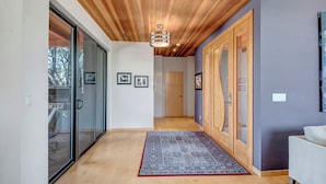 A hallway with wooden flooring, a patterned rug, and a ceiling with wooden beams.
