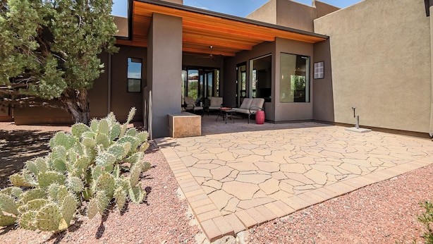 A modern house with a patio area, outdoor seating, and a cactus plant.