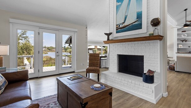 A spacious living room with a fireplace, a large window, and a view of the outdoors.