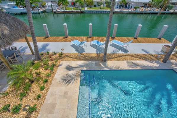 A pool area with lounge chairs, a wooden deck, and a view of the marina.