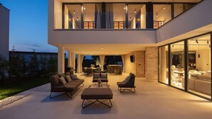 A modern outdoor living area with a sofa set, a dining table, and a grill. - Cozy home in Rovinjsko Selo with sauna (Rovinjsko Selo)