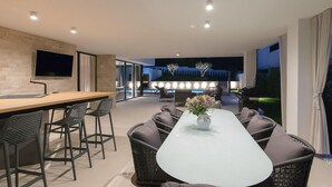 A modern kitchen with a large island, bar seating, and a dining area with a glass-top table and chairs. - Cozy home in Rovinjsko Selo with sauna (Rovinjsko Selo)