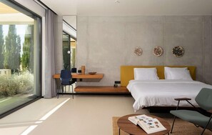 Une chambre moderne avec un grand lit, un bureau et une vue sur la verdure.