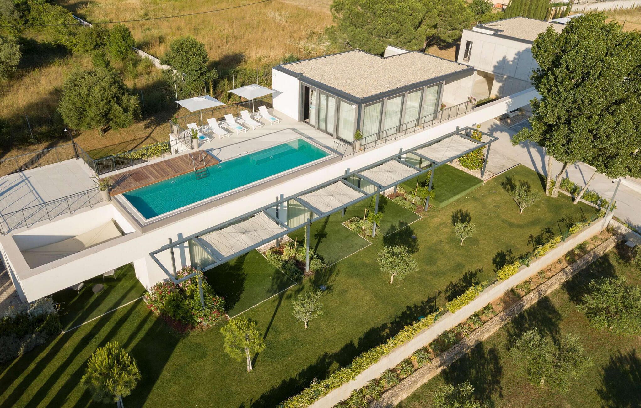 Een modern huis met een zwembad, terras en een verzorgde tuin.
