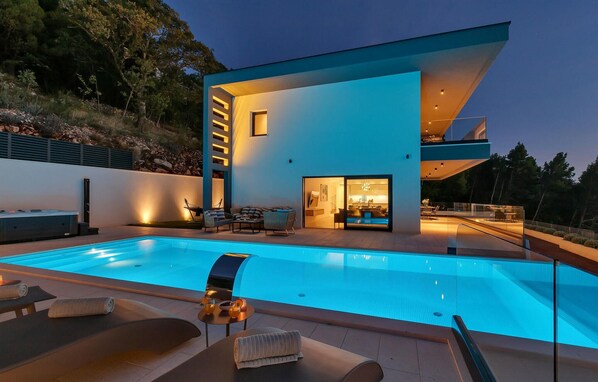 Une maison moderne dotée d’une piscine, d’un espace extérieur aménagé et d’un intérieur bien éclairé.