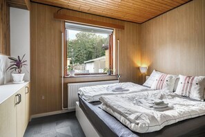 Une chambre à coucher avec un lit, une table de chevet, une fenêtre et une vue sur l’extérieur.