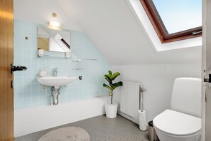 A bathroom with a skylight, white sink, and toilet. - Cozy house close to Lalandia and Rødby Harbour (Rødby)
