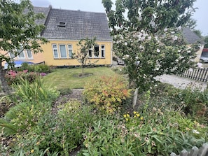 A residential house with a well-maintained garden, a small tree, and a visible window. - Cozy house close to Lalandia and Rødby Harbour (Rødby)