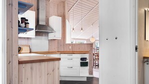 A modern kitchen with wooden cabinetry, a built-in stove, and a hanging light fixture.