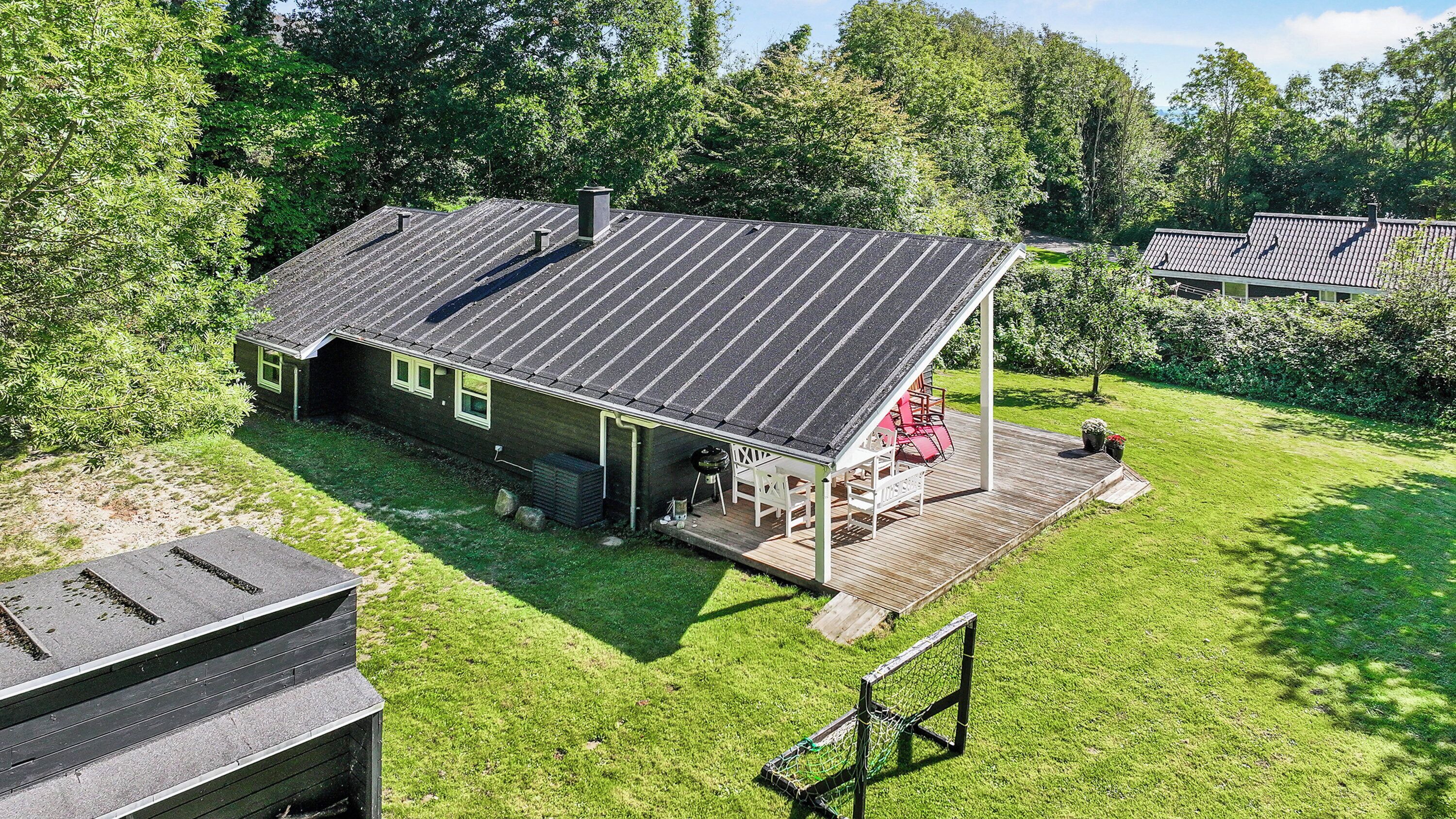 A house with a covered patio, a lawn, and a deck.