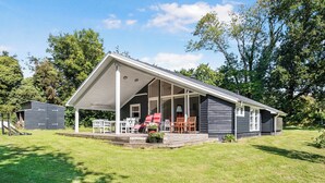 A house with a covered porch, a small shed, and a lawn.