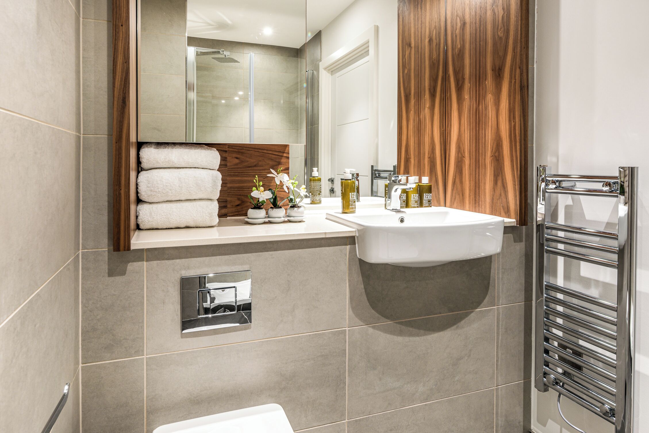 A modern bathroom with a built-in sink, a towel rack, and a glass shower enclosure.