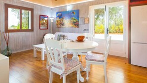 Un coin repas avec une table ronde, des chaises blanches et un tableau accroché au mur.