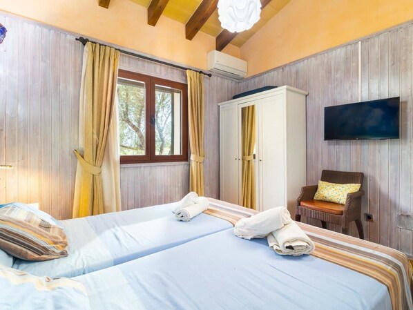 A bedroom with two beds, a wardrobe, a TV, and a window with curtains. - Beautiful finca with private pool in Santa Margalida (Santa Margalida)