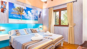 Une chambre d’hôtel avec deux lits, un grand tableau sur le thème de la plage, un plancher en bois et une fenêtre avec des rideaux.