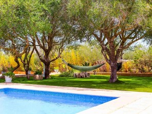 Une piscine entourée d’une végétation luxuriante et d’arbres.