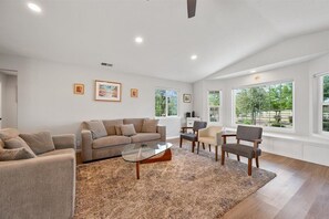 Un salon moderne avec un canapé, des fauteuils, une table basse et des œuvres d’art accrochées aux murs.