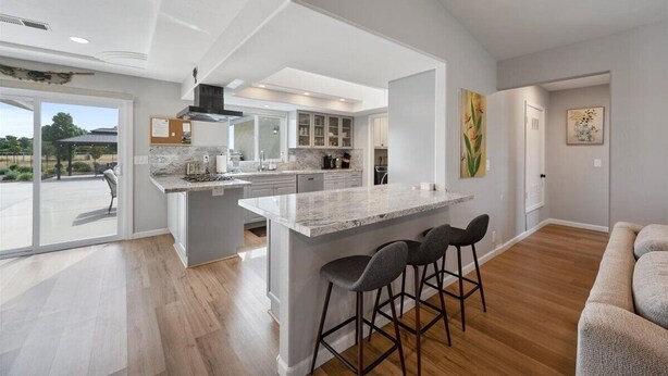 A modern kitchen with an island, bar stools, and a view to the outside. - Newly remodeled 4-bedroom, 3-bathroom home with jacuzzi close to downtown Paso (Paso Robles)