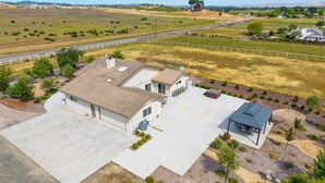 A residential property with a large garage, a covered outdoor seating area, and a well-maintained lawn. - Newly remodeled 4-bedroom, 3-bathroom home with jacuzzi close to downtown Paso (Paso Robles)