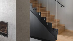 A modern staircase with wooden steps and black handrails, leading to a landing area with a fireplace. - Cozy home in Labin with WiFi (Labin)