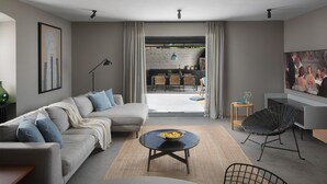 A modern living room with a sofa, coffee table, and chairs, a dining area with a table and chairs, and a TV on the wall. - Cozy home in Labin with WiFi (Labin)