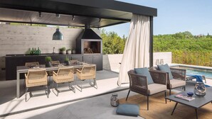 An outdoor kitchen area with a dining set, a grill, and a poolside seating area. - Cozy home in Labin with WiFi (Labin)