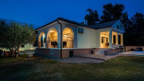 Una casa de dos pisos con un patio, una piscina y un interior bien iluminado.