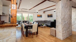 Amplia sala de estar con mesa de comedor, sofás y una pared de acento de piedra.