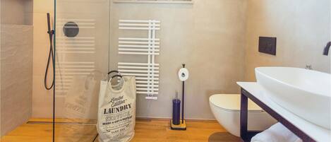 A modern bathroom with a glass shower enclosure, a toilet, and a sink.