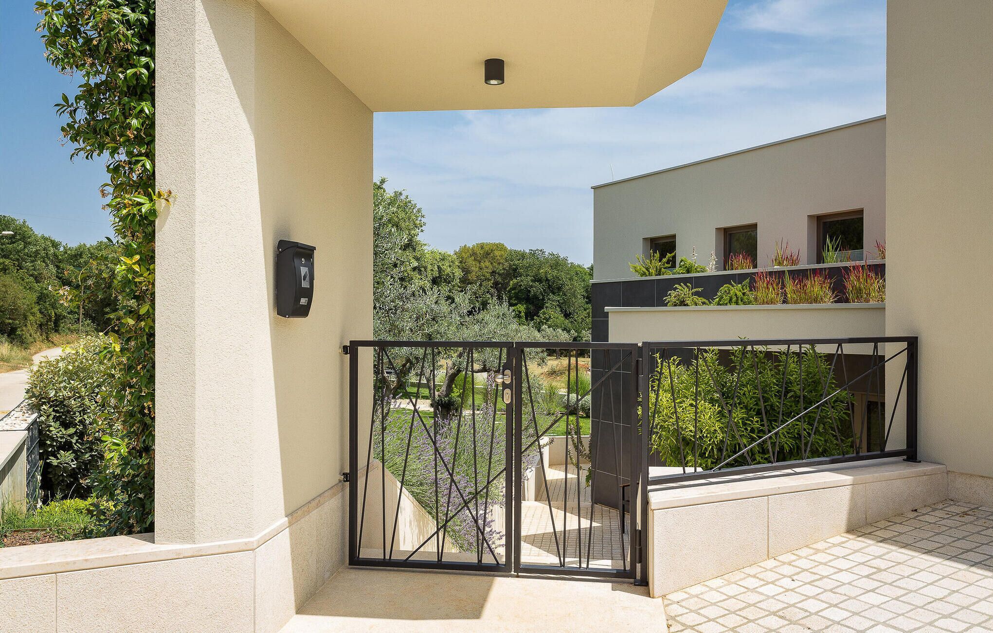 A modern building with a balcony, a gate, and a small garden area.