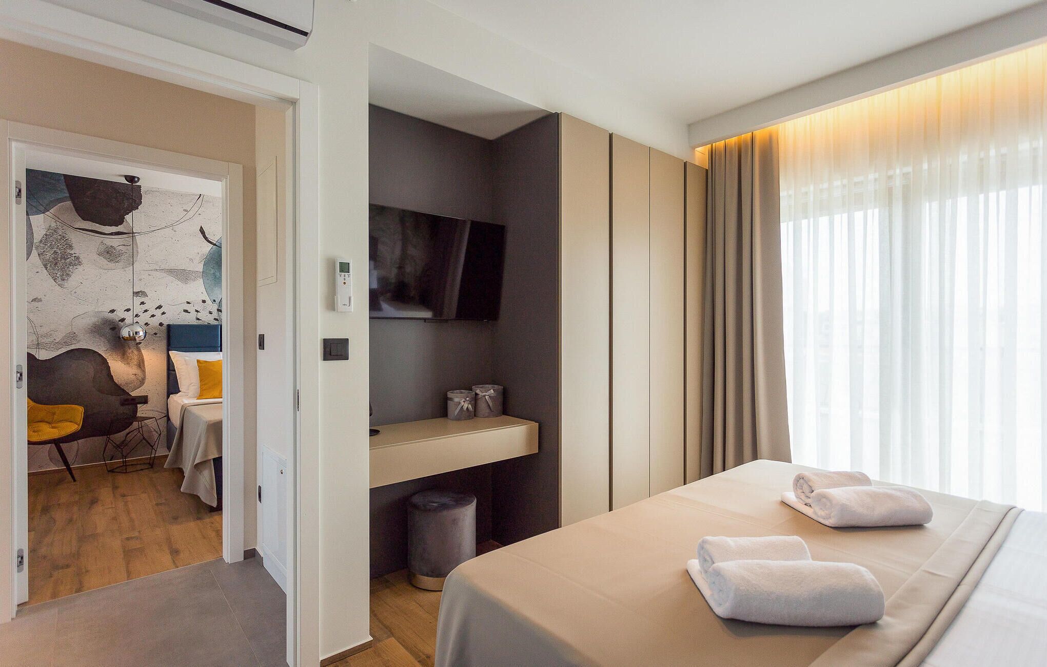 A modern hotel room with a bed, a desk, a chair, and a television.
