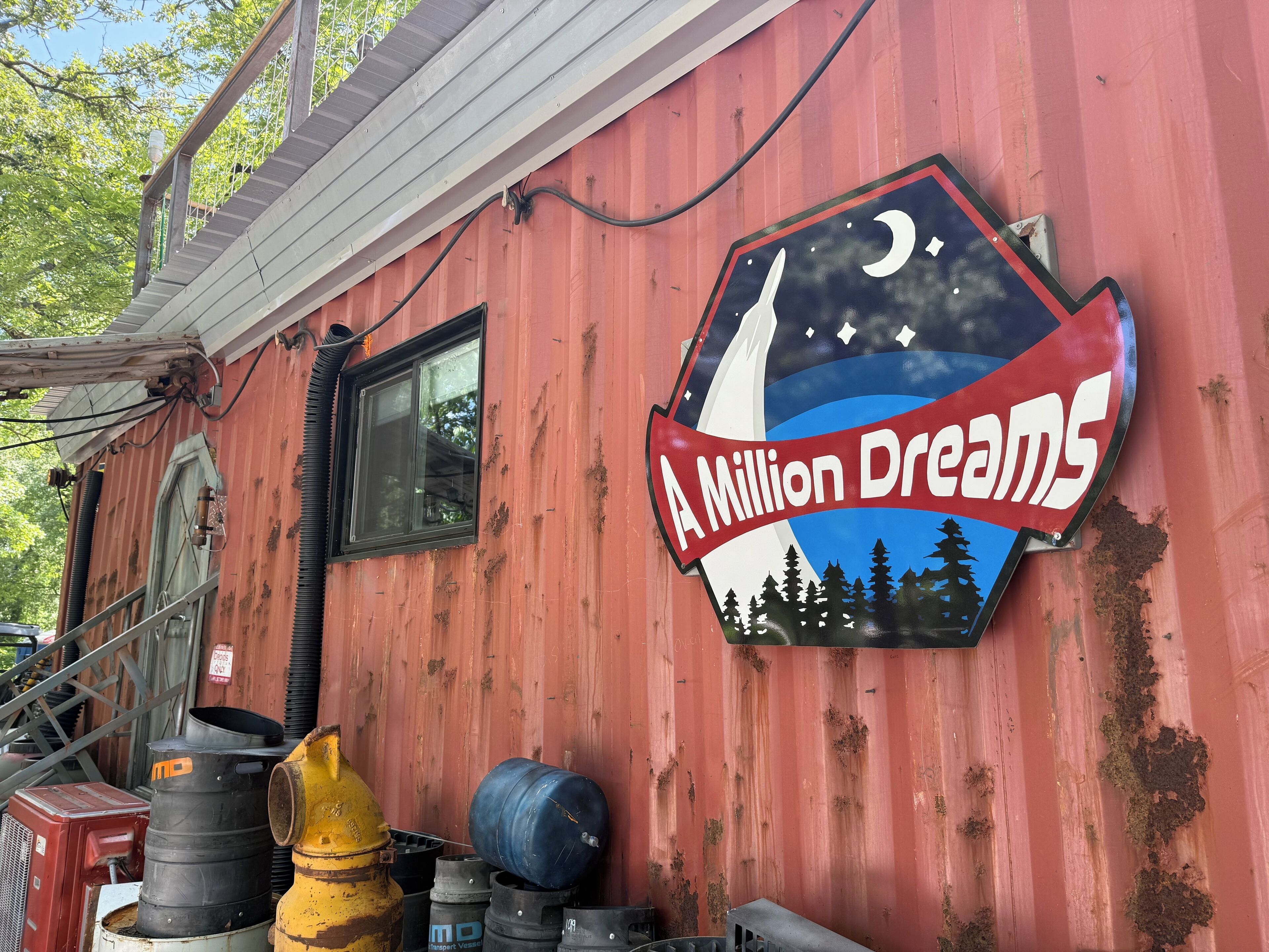 Ein rotes Gebäude mit einem Schild, auf dem 'A Million Dreams' steht, und einem Logo mit Segelboot und Bäumen.