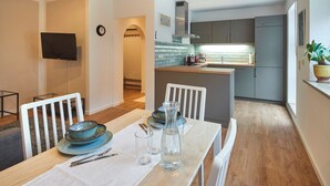 A modern kitchen with grey cabinets, a stainless steel range hood, and a built-in oven. - Ferienwohnung Rosengasse 3, bis 4 Personen, 50qm, Terrasse (Bad Reichenhall)