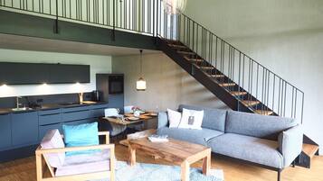 Ein moderner Wohnraum mit Küche, Essbereich und Treppe.