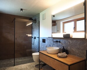 A modern bathroom with a glass-enclosed shower, a wooden vanity, a large mirror, and a built-in sink. - Ferienwohnung Riesenkopf (Brannenburg)