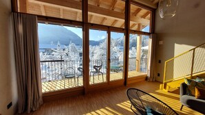 A room with large windows offering a view of snow-covered trees and mountains.