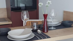Eine moderne Küche mit einem Esstisch für zwei Personen, einer roten Vase mit Blumen und einer schwarzen Pendelleuchte.