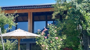 Ein Gebäude mit großen Fenstern, einem Balkon und einem Garten mit rosa Rosen.