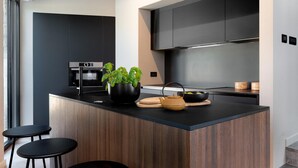 Una cocina moderna con una isla central, armarios negros y un horno empotrado.