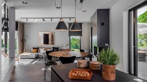 Un comedor moderno con una mesa redonda, sillas negras e iluminación colgante.