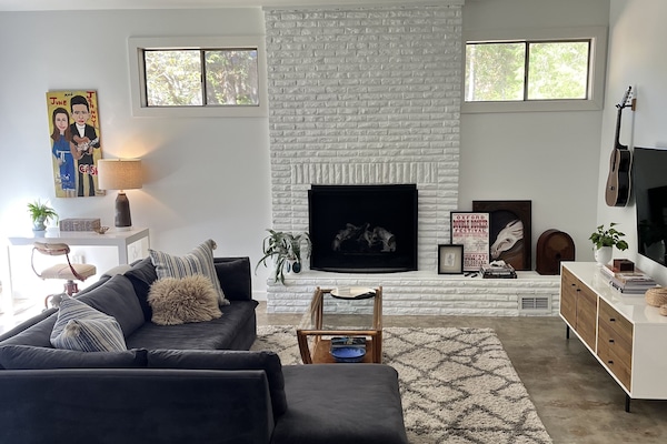 Large sunlit sunken den with sectional seating, 65" smart TV, and desk.
