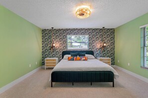 Une chambre à coucher avec un lit, deux tables de chevet, une fenêtre et un luminaire au plafond.