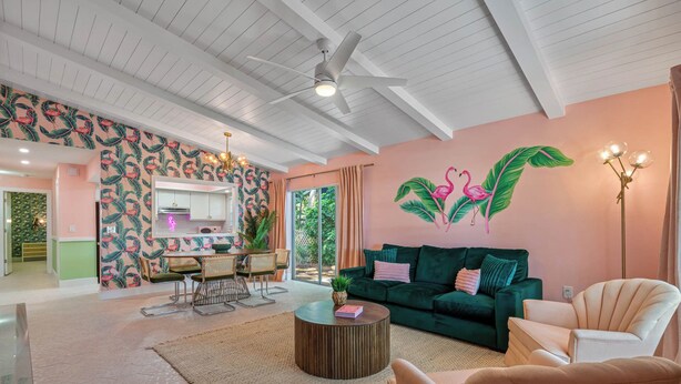 Ein modernes Wohnzimmer mit einem grünen Sofa, einem runden Couchtisch und einem Essbereich mit weißem Tisch und Stühlen.