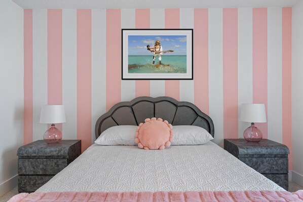 Une chambre à coucher avec un lit, deux tables de chevet, une tête de lit et un tableau encadré au mur.