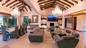 A spacious living room with a fireplace, a dining area with a large table and chairs, and a modern chandelier. - Llano Grande (Rionegro)